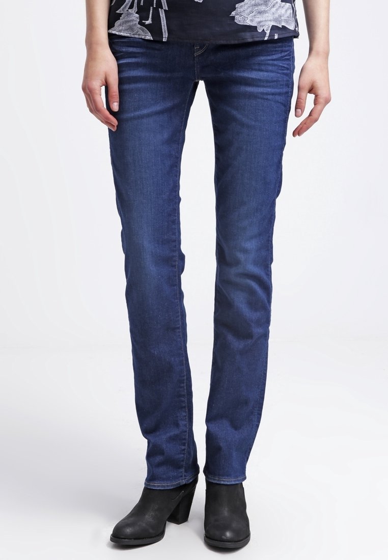 Modré úzké džíny z denimu s pasem ve střední výšce, pětiprvkovým designem kapes a mírným strečem pro pohodlí, doplněné černými kotníkovými botami.