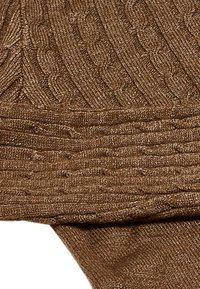 Tessuto a maglia marrone caratterizzato da un motivo a treccia testurizzato. Il materiale appare morbido, con sezioni a costine di diverse dimensioni che mostrano profondità e dettaglio.