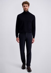 Marineblauwe coltrui en donkere broek, beide nauwsluitend. Schoenen zijn donkerbruin met een gladde textuur. Eenvoudig, gestroomlijnd ontwerp.