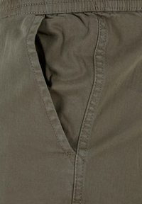 Olive green cotton fabric with a textured finish, featuring a side pocket and stitched seams. Simple, functional design.
