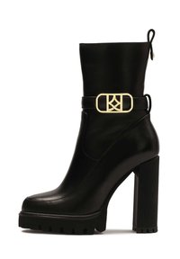 Black leather ankle boot with a chunky high heel, featuring a gold buckle accent and a textured sole for added grip.