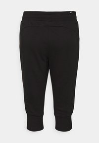 Calças jogger pretas, curtas, feitas de tecido macio, com uma cintura elástica e punhos ajustados. Detalhes em costura na parte de trás acrescentam um toque de design subtil.