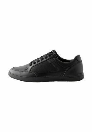 Black sneaker with a smooth leather upper, mesh panel on the side, rounded toe, six eyelets, and a flat rubber sole.