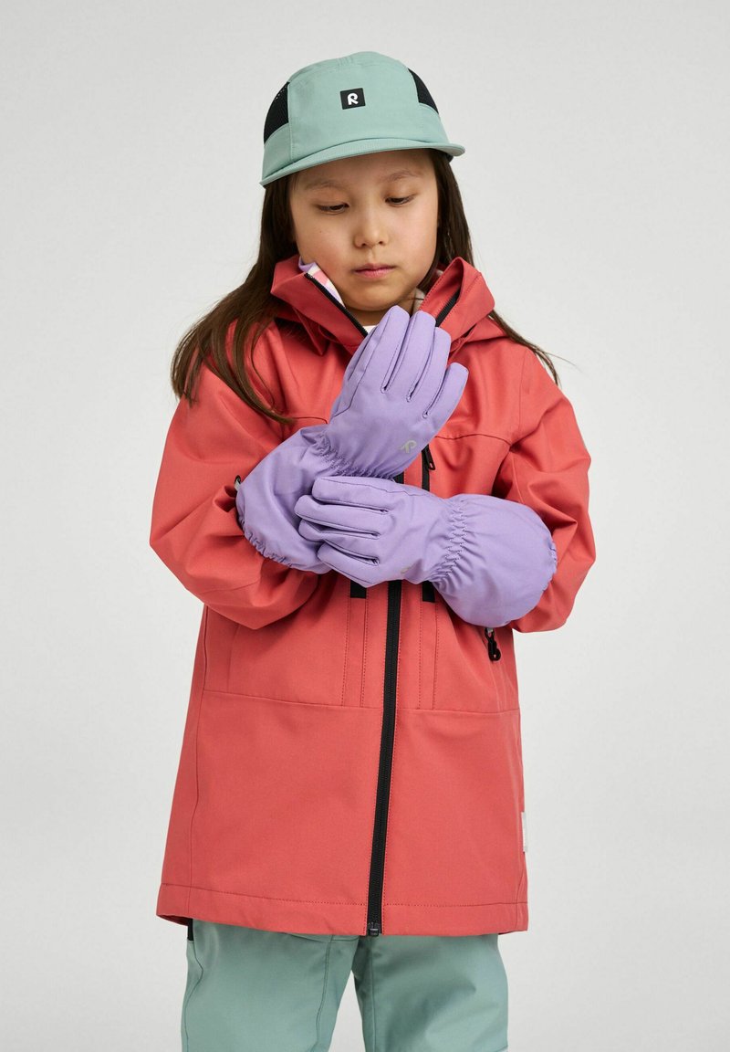 Veste imperméable rouge avec une fermeture éclair noire, associée à des gants lavande. Une casquette bleu clair complète la tenue, avec un petit logo.