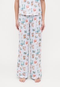 Ensemble de pyjama en tissu lisse et léger. Présente une base blanche avec un imprimé de paysage urbain coloré en bleu, rose et orange. Les pantalons sont à jambes larges.