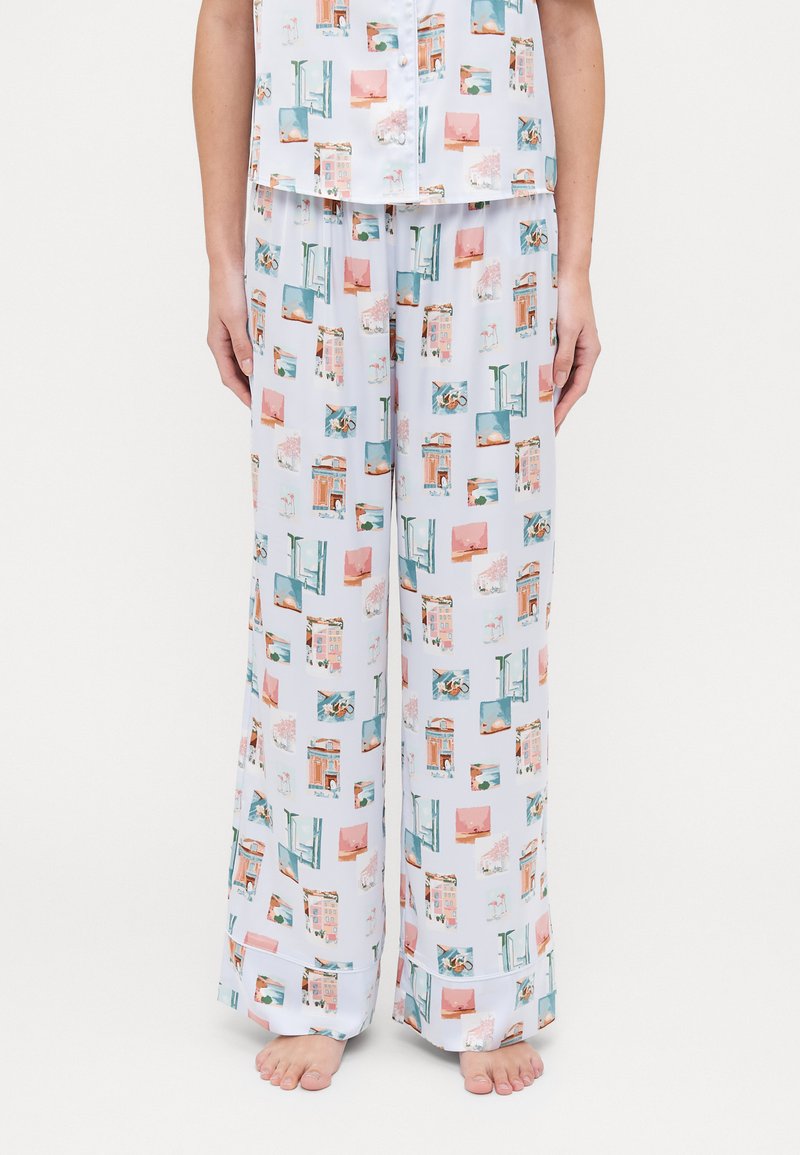 Ensemble de pyjama en tissu lisse et léger. Présente une base blanche avec un imprimé de paysage urbain coloré en bleu, rose et orange. Les pantalons sont à jambes larges.