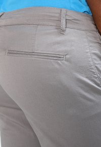 Jasnoszare spodnie o gładkiej fakturze, z pojedynczą tylną kieszenią i czystym, dopasowanym krojem, odpowiednie na różne okazje.