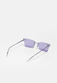 Occhiali da sole con lenti angolari di colore viola, montatura in metallo argentato e aste sottili. Caratteristiche includono cuscinetti per il naso e un logo discreto sulla lente.