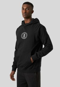Czarna bluza z kapturem wykonana z miękkiego materiału, z przednią kieszenią kangurką i białym logo graficznym na klatce piersiowej. Dopasowane mankiety i kaptur ze sznurkiem.