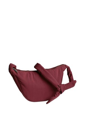 Sac bandoulière en tissu bordeaux avec une sangle ajustable nouée et une fermeture zippée sur le dessus, sur fond blanc.