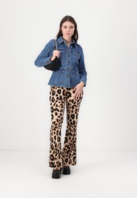 Denim jope nupuvõttega, kaks rinnataskut; lehvikukujulised leopardimustrilised püksid pruunis ja mustas; must käekott ketiga; paksude kandadega kingad.