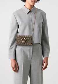 Small rectangular crossbody bag in brown fabric with ornate pattern, gold hardware clasp, and a detachable chain strap.