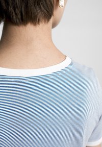 Camiseta a rayas azul y blanca con cuello redondo, hecha de una tela suave. Sus características notables incluyen un cuello blanco y una textura suave.