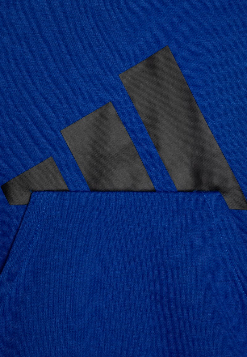 Felpa blu realizzata in morbido tessuto, con un grande logo nero testurizzato e una tasca frontale. Il design include forme angolari.