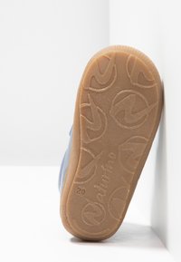 Modrá bota s hladkým svrškem, gumovou podrážkou s texturovaným gripem a kruhovými vzory, mírně opotřebovaná, nakloněná proti bílému pozadí.