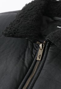Black leather jacket featuring a textured black fleece collar, prominent zipper with metallic detail, and smooth leather body.
