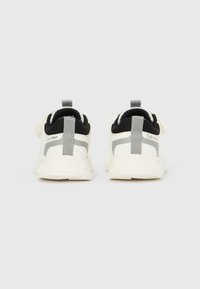 Par de sapatilhas Calvin Klein brancas e cinzentas vistas de trás, mostrando o forro interior preto e as abas para puxar no calcanhar.