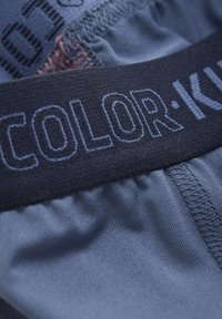 Boxershortar med en m�örkblå midja som har "COLOR·K" i ljusblått. Mjukt tyg med en slät textur och sydda detaljer.