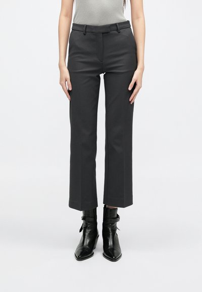 Kohandatud mustad püksid laiade jalgadega, sileda esiosa ja vööpaeltega. Valmistatud siledast kangast, klassikalise lõikega ja neutraalse värviga.