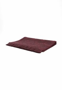 Bordowy koc z tkaniny o teksturowanym, plecionym wzorze, z frędzlami na brzegu i złożonym designem, co dodaje głębi jego wyglądowi.