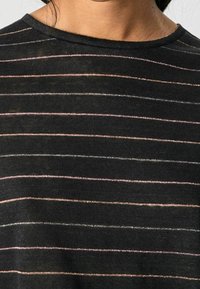 Sort T-shirt med horisontale metalliske striber i lys pink og sølv. Blød tekstur med rund halsudskæring og korte ærmer.
