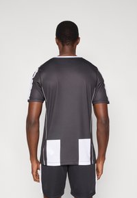 Kortærmet atletisk skjorte i mørkegrå med hvide sidepaneler og kantdetaljer, har rund halsudskæring og tekstureret stof.