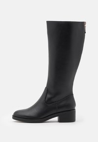 Bottes en cuir noires arrivant au genou, avec un bout arrondi, une fermeture éclair sur le côté et un talon bloc. Texture lisse avec des détails de coutures minimaux.