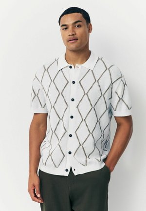 Weißer kurzärmeliger Cardigan mit einem Rautenmuster in Braun, mit einer Knopfverschluss-Front und einem klassischen Kragen. Strukturierter Strickstoff.