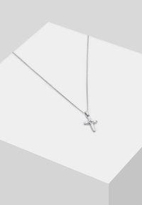 Silbernes Kreuzhalsband mit einer zarten Kette, das ein poliertes Finish und ein einfaches Design aufweist, auf einer hellgrauen geometrischen Oberfläche präsentiert.