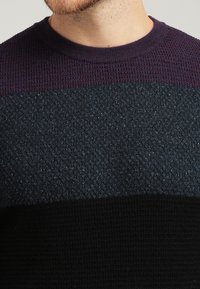 Czarny sweter z dzianiny z poziomymi pasami w ciemnym fioletowym, granatowym i czarnym kolorze. Teksturowana tkanina z delikatnym efektem połysku.
