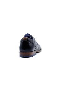 Chaussure en cuir noir avec une finition lisse, accent en cuir brun au talon et doublure en textile bleu. Profil bas avec une semelle en caoutchouc durable.