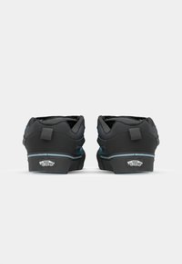 Zwarte skate schoenen met een gevoerde kraag, een gestructureerde bovenkant, blauwe accenten en een rubberen zool met het Vans-logo op de hak.