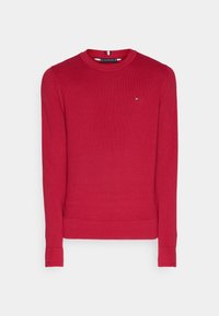 Suéter de punto rojo con cuello redondo, puños y dobladillo acanalados. Presenta un pequeño logo en el lado izquierdo del pecho y acentos a rayas en el interior del cuello.