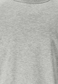 Grå t-shirt lavet af blødt bomuldsblandingsmateriale. Har rund halsudskæring og en glat, let struktureret overflade. Ingen mønstre eller grafik.