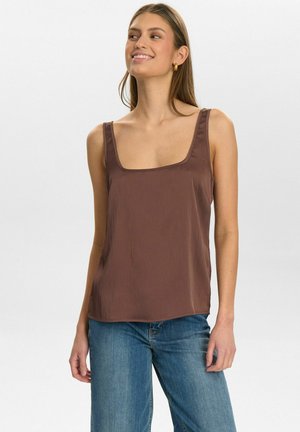 Brown sleeveless top with a square neckline and textured fabric. Worn with blue high-waisted jeans, featuring a relaxed fit.