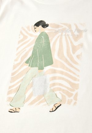 Femme aux cheveux bruns attachés en chignon, portant une veste verte, un pantalon clair et des sandales, marchant avec un sac fourre-tout devant un fond abstrait beige.