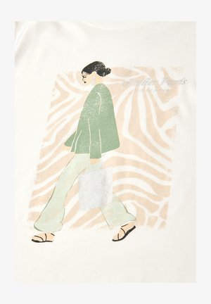 Kobieta z ciemnymi włosami związanymi w koczek, ubrana w zieloną kurtkę, jasne spodnie i sandały, idąca z torbą na ramię na tle beżowego, abstrakcyjnego tła.