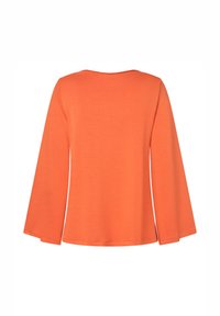 Oranges langärmliges Oberteil mit Rundhalsausschnitt und lockerer Passform. Weicher, glatter Stoff mit subtiler Textur; die Ärmel reichen leicht über die Handgelenke hinaus.