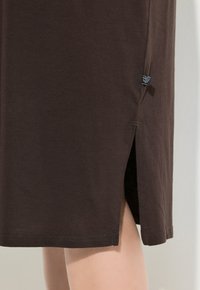 Abito in cotone marrone con spacchi laterali. Presenta una trama liscia e cuciture sottili all'orlo. Etichetta visibile di lato.