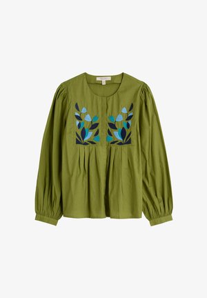 Blusa de algodón verde con mangas largas y abullonadas. Presenta diseños florales bordados en azul y negro en el pecho, y detalles con pliegues.