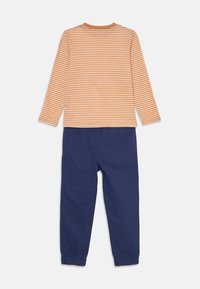 Cămașă cu mânecă lungă, dungi portocalii și albe, cu guler rotund, asociată cu pantaloni de culoare albastru închis, cu manșete elastice la glezne.