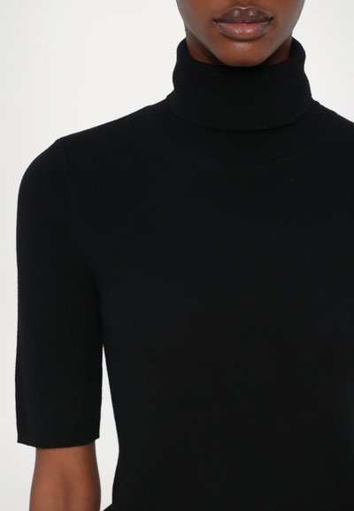 Svart polotröja med korta ärmar, tillverkad av ribbat tyg, med en figurnära design och slät yta. Inga synliga mönster eller accenter.