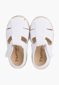 White espadrille-style shoes with woven canvas upper, featuring cut-out details and adjustable strap, set on a natural jute sole.