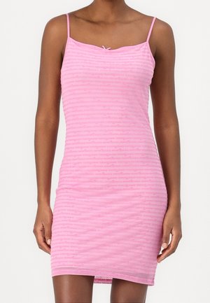 Mujer con vestido rosa ajustado sin mangas, con tirantes finos y un pequeño detalle de lazo en el escote.