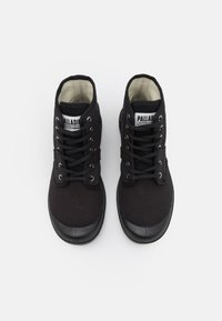Botas de tobillo de lienzo negro con apariencia texturizada, puntera redonda y suelas de goma. Presentan ojales plateados y cordones negros. Etiqueta de la marca visible.