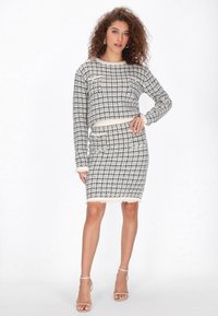 Fekete-fehér houndstooth kötött szett, amely egy fazonra szabott, francia szélű cropped pulóvert és egy testhez simuló, diszkrét zsebelésű szoknyát tartalmaz.