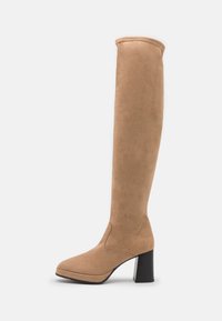 Cizme din sueded bej până la genunchi, cu vârf pătrat și toc gros negru. Textura este netedă, cu cusături minime și un design elegant.