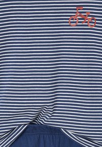 Navy- und weiß gestrefter Stoff mit einem kleinen roten Fahrrad-Icon in der oberen rechten Ecke, am unteren Rand teilweise gefaltet.