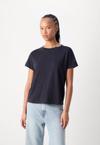 Navyblauw katoenen t-shirt met korte mouwen, een ronde halslijn en een relaxte pasvorm, gecombineerd met lichtgewassen denim jeans.