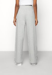 Pantalones de pierna ancha en gris, confeccionados con una tela suave y cinturilla elástica, con un dobladillo ligeramente acampanado y detalles de costura mínimos.